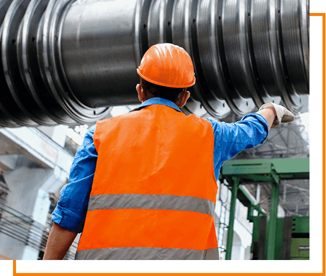 A man in an orange vest and hard hat standing next to a large metal object.